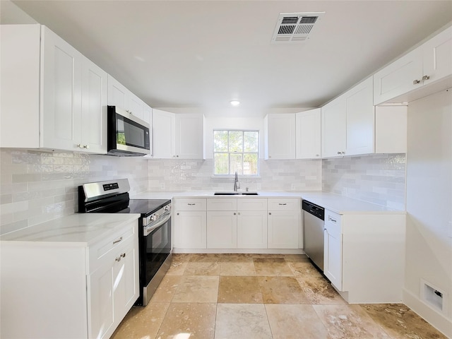 kitchen featuring white cabinets, appliances with stainless steel finishes, backsplash, and sink