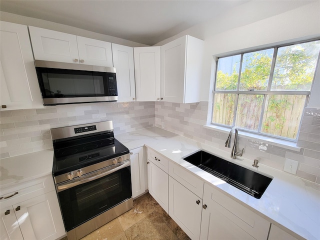 kitchen featuring light stone countertops, sink, white cabinets, and appliances with stainless steel finishes