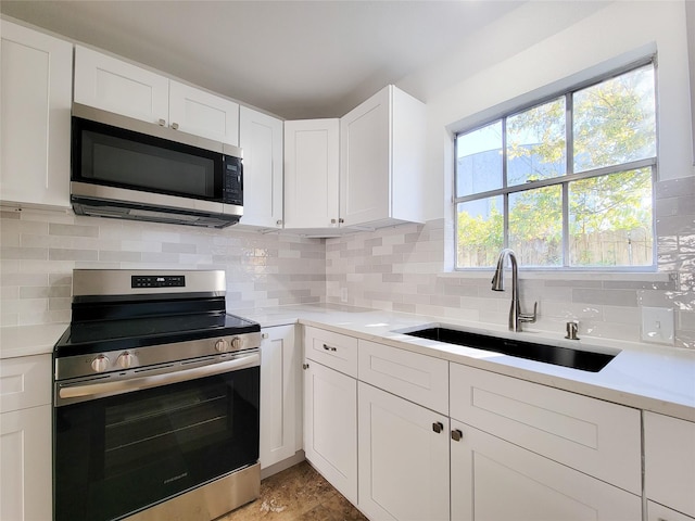 kitchen featuring tasteful backsplash, white cabinetry, sink, and appliances with stainless steel finishes