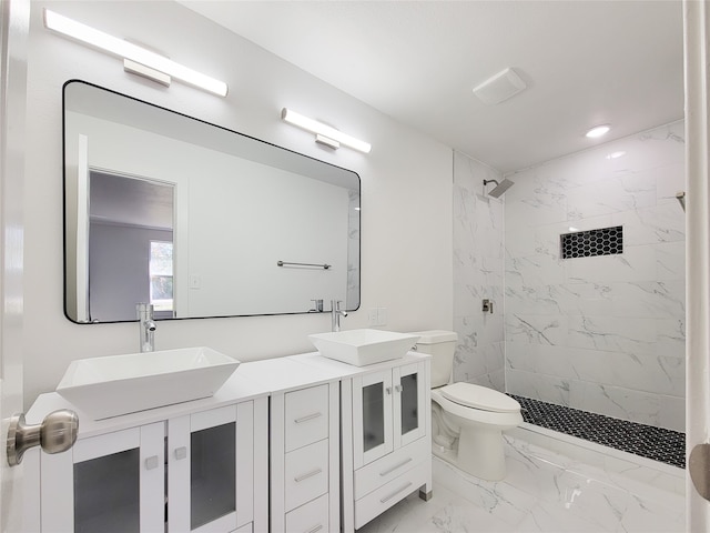 bathroom with vanity, toilet, and tiled shower