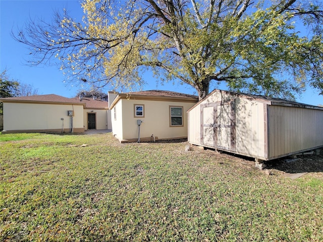 rear view of house with a yard and a storage unit