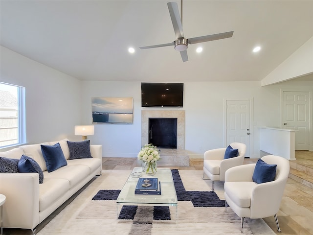 living room featuring ceiling fan, lofted ceiling, and a tile fireplace