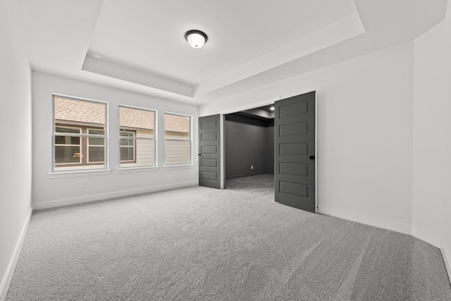 unfurnished bedroom featuring a raised ceiling and carpet floors