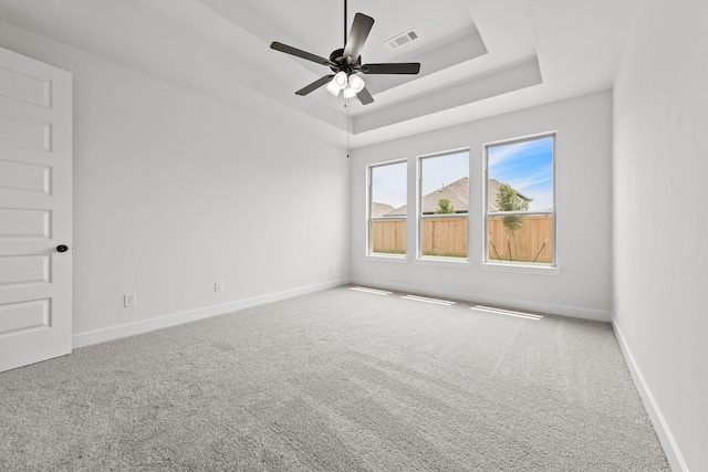 unfurnished room featuring a tray ceiling, ceiling fan, and carpet