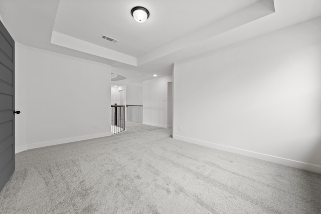 carpeted empty room featuring a tray ceiling