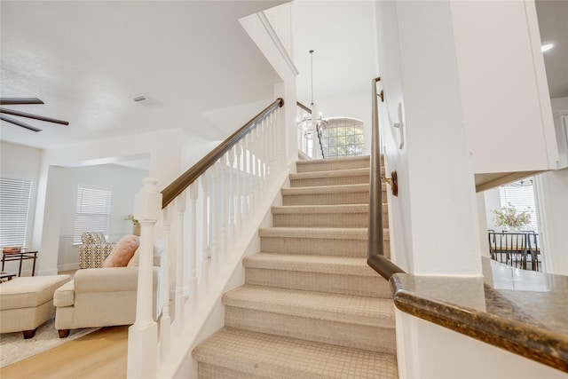 stairs featuring wood-type flooring and an inviting chandelier