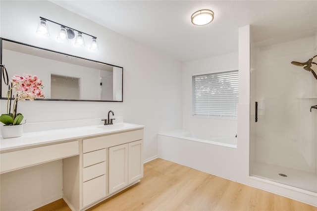 bathroom featuring vanity, hardwood / wood-style floors, and plus walk in shower