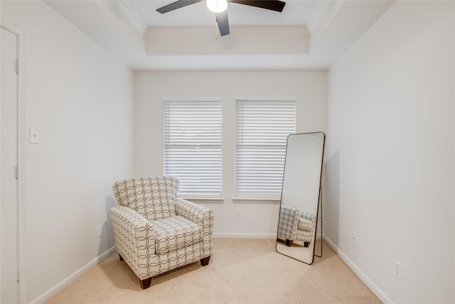 living area featuring a raised ceiling, ceiling fan, carpet, and ornamental molding