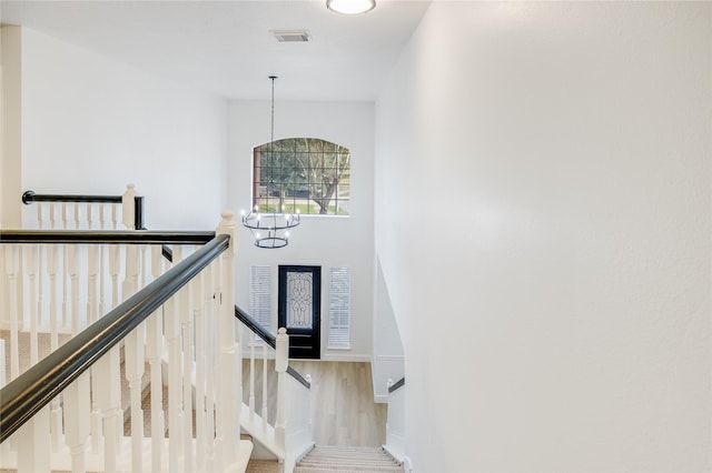 stairs featuring hardwood / wood-style floors and a notable chandelier