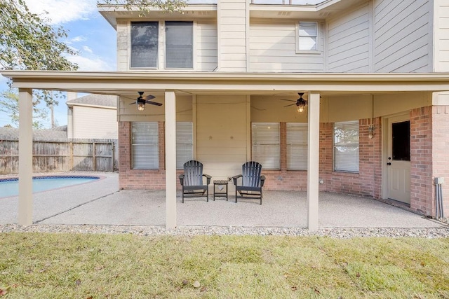 back of property featuring ceiling fan, a patio area, and a fenced in pool