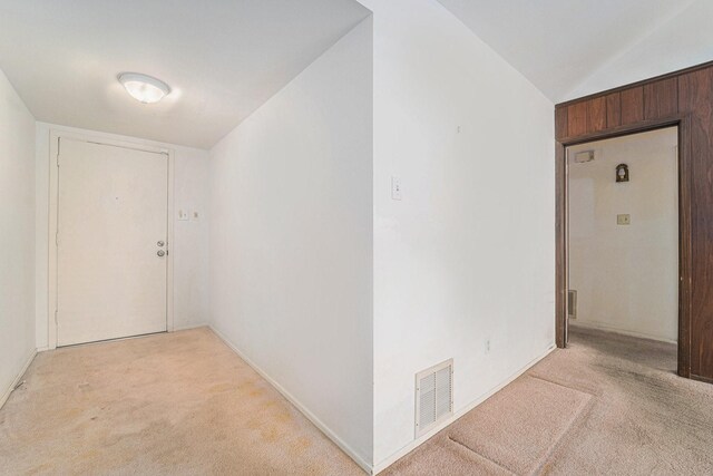 hall featuring light colored carpet and lofted ceiling