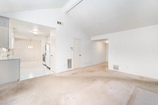 empty room with light carpet, visible vents, and beamed ceiling