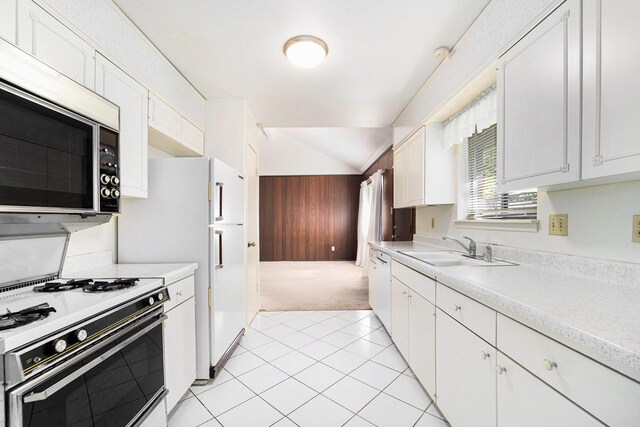 kitchen with white appliances, vaulted ceiling, sink, light tile patterned floors, and white cabinets