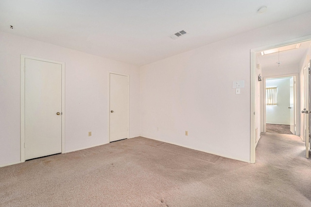unfurnished room featuring attic access, light colored carpet, and visible vents