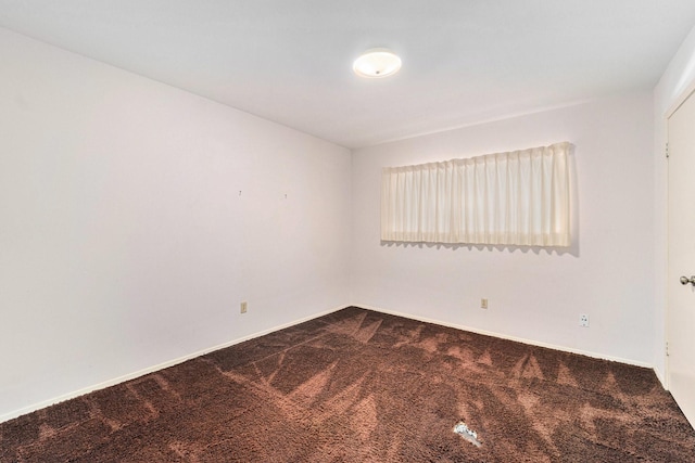 empty room with dark carpet and baseboards