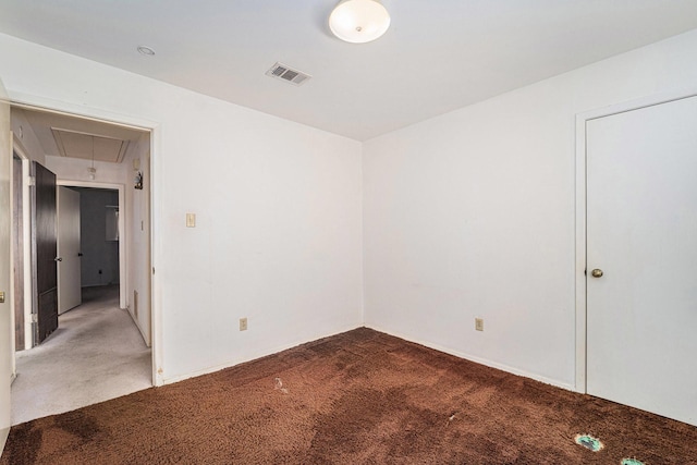 empty room with visible vents, light colored carpet, and attic access