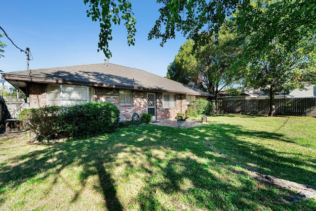 back of house featuring a yard, a patio, brick siding, and a fenced backyard