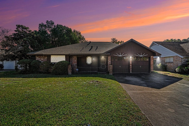 ranch-style home with driveway, a yard, a shingled roof, a garage, and brick siding