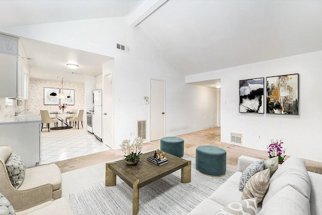 living area featuring beam ceiling, light tile patterned floors, light colored carpet, and visible vents