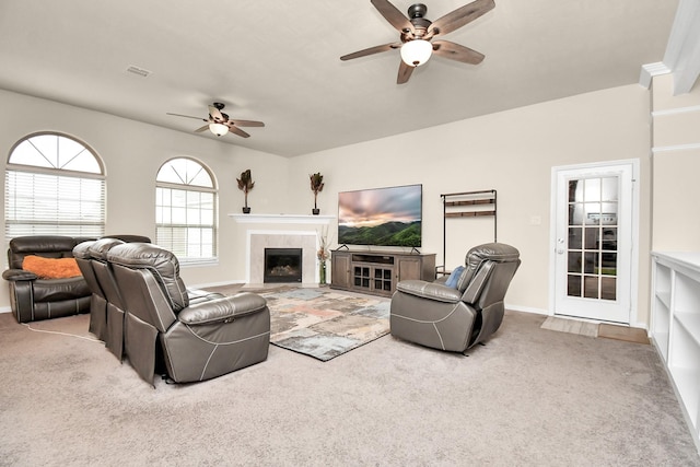 carpeted living room with ceiling fan, crown molding, and a tiled fireplace