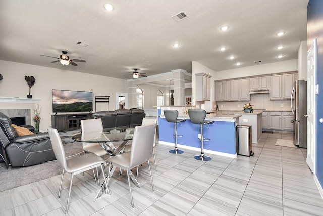 dining area featuring a tile fireplace, ceiling fan, and light tile patterned floors