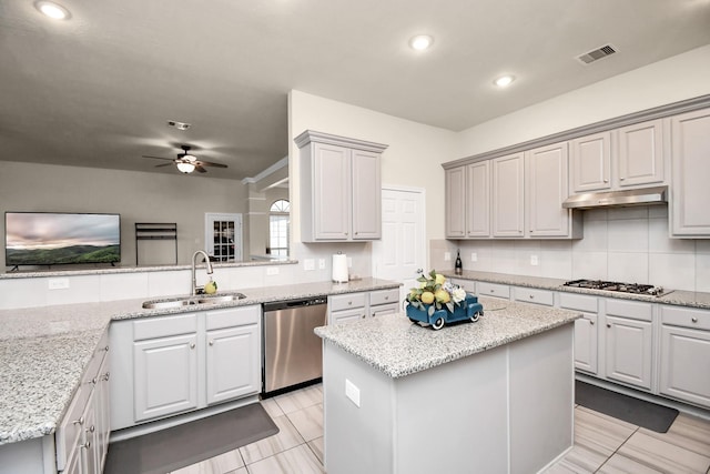 kitchen with kitchen peninsula, appliances with stainless steel finishes, a kitchen island, and sink