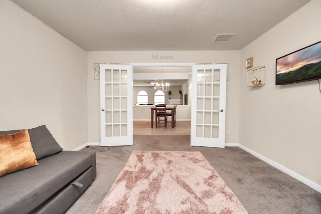 living area with french doors, carpet, and a textured ceiling