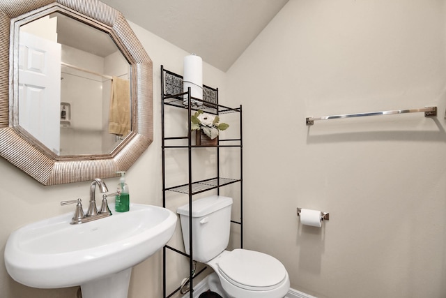 bathroom with toilet, vaulted ceiling, and sink