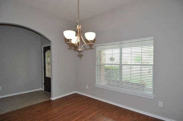 empty room featuring dark wood-type flooring, vaulted ceiling, and a notable chandelier