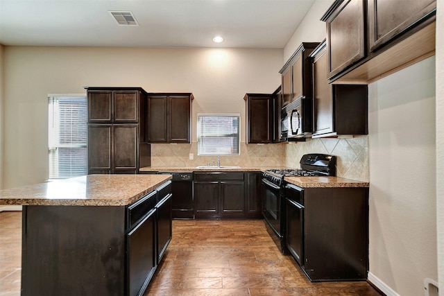 kitchen featuring sink, plenty of natural light, dark wood-type flooring, and black appliances