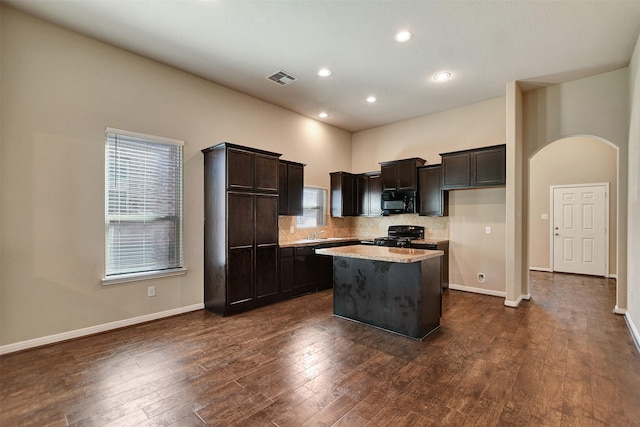 kitchen with dark brown cabinetry, dark hardwood / wood-style floors, a kitchen island, and black appliances