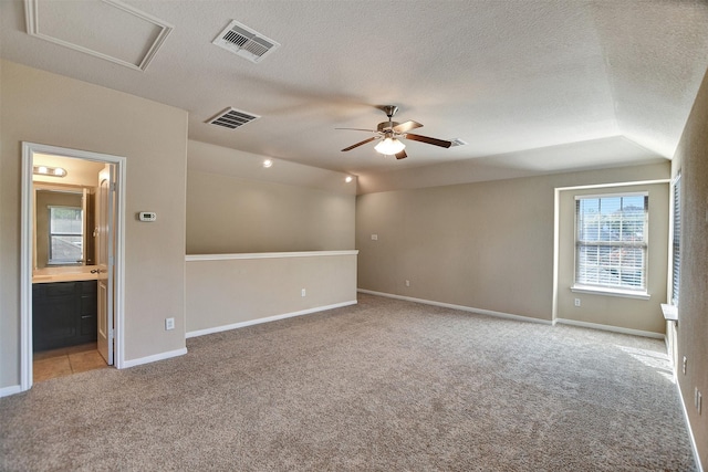 unfurnished room featuring ceiling fan, light colored carpet, lofted ceiling, and a textured ceiling