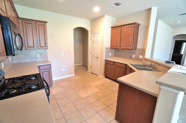 kitchen featuring sink, decorative backsplash, light tile patterned floors, kitchen peninsula, and range with gas cooktop