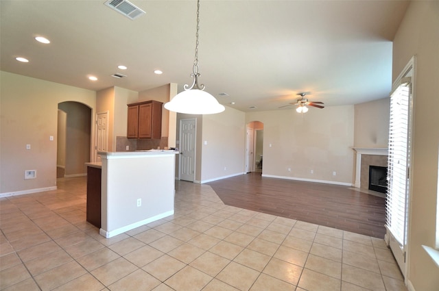 kitchen with ceiling fan, a fireplace, decorative light fixtures, and light hardwood / wood-style flooring