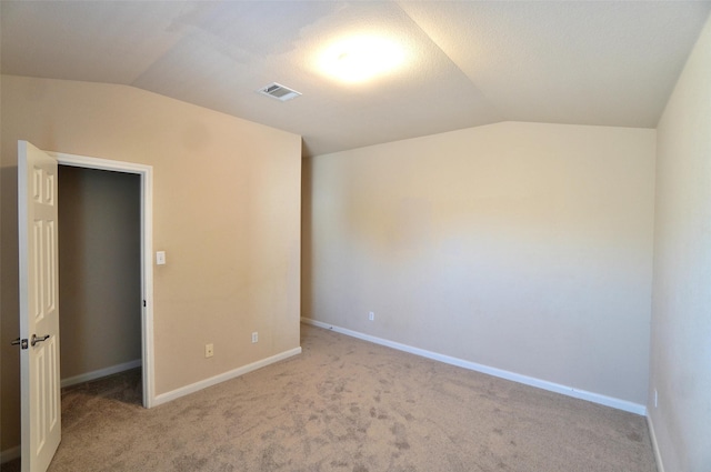 empty room with light carpet and vaulted ceiling