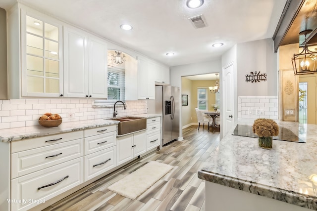 kitchen with white cabinetry, sink, light stone counters, stainless steel refrigerator with ice dispenser, and light hardwood / wood-style floors