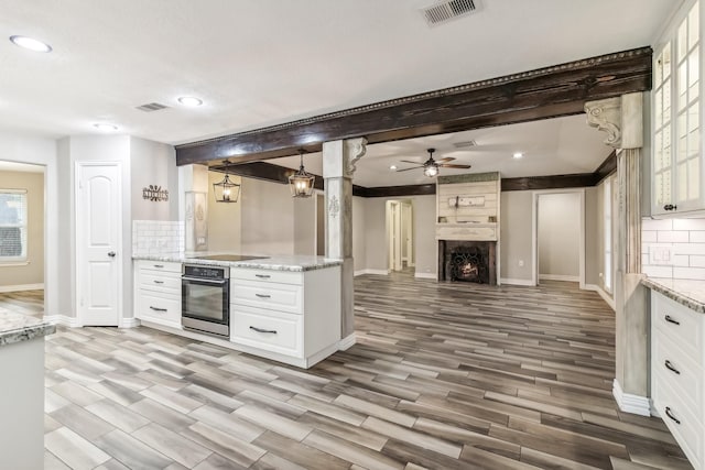 kitchen featuring white cabinets, oven, light wood-type flooring, and backsplash