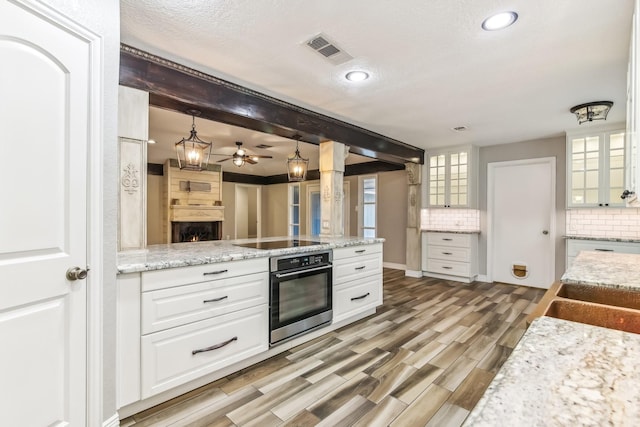 kitchen featuring white cabinetry, hardwood / wood-style floors, oven, and decorative light fixtures