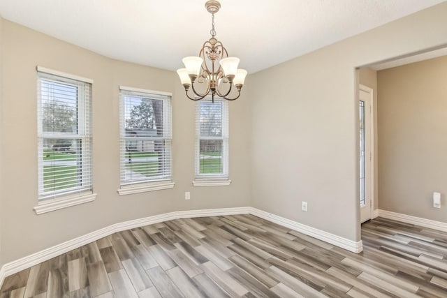 spare room featuring hardwood / wood-style floors and an inviting chandelier