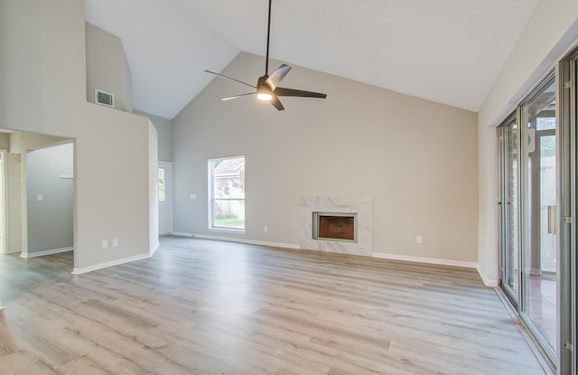 unfurnished living room with ceiling fan, a fireplace, high vaulted ceiling, and light wood-type flooring