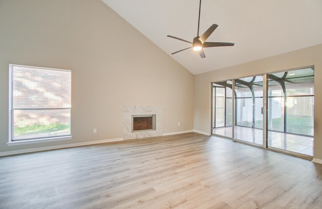 unfurnished living room featuring ceiling fan, light wood-type flooring, a fireplace, and high vaulted ceiling