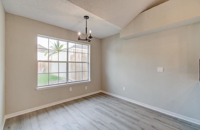 unfurnished dining area with lofted ceiling, light hardwood / wood-style floors, a healthy amount of sunlight, and a notable chandelier