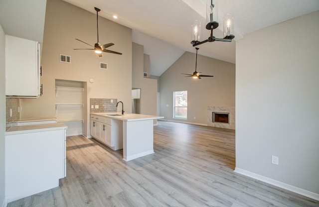 kitchen featuring decorative backsplash, light wood-type flooring, white cabinetry, and high vaulted ceiling