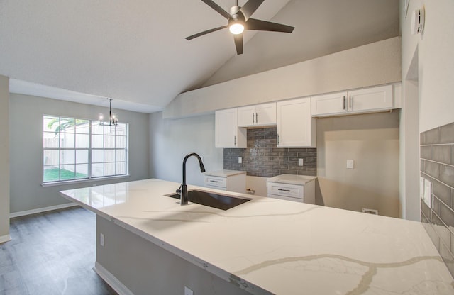 kitchen with high vaulted ceiling, white cabinets, sink, decorative light fixtures, and dark hardwood / wood-style flooring