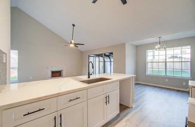 kitchen featuring white cabinets, light hardwood / wood-style floors, light stone countertops, and sink