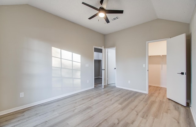 unfurnished bedroom featuring a walk in closet, vaulted ceiling, ceiling fan, light hardwood / wood-style floors, and a closet