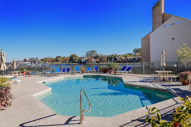 view of pool with a water view and a patio