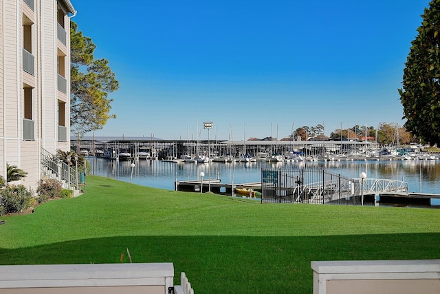 view of dock with a yard and a water view