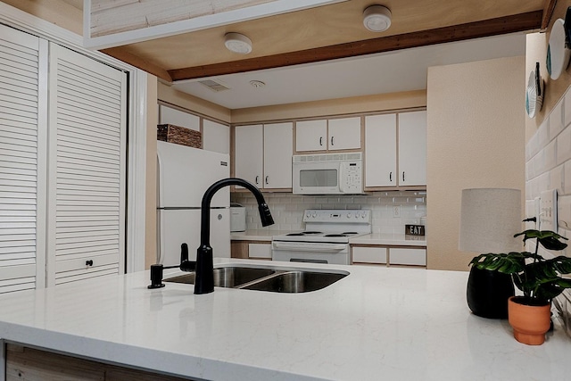 kitchen featuring white appliances, sink, tasteful backsplash, beam ceiling, and white cabinetry