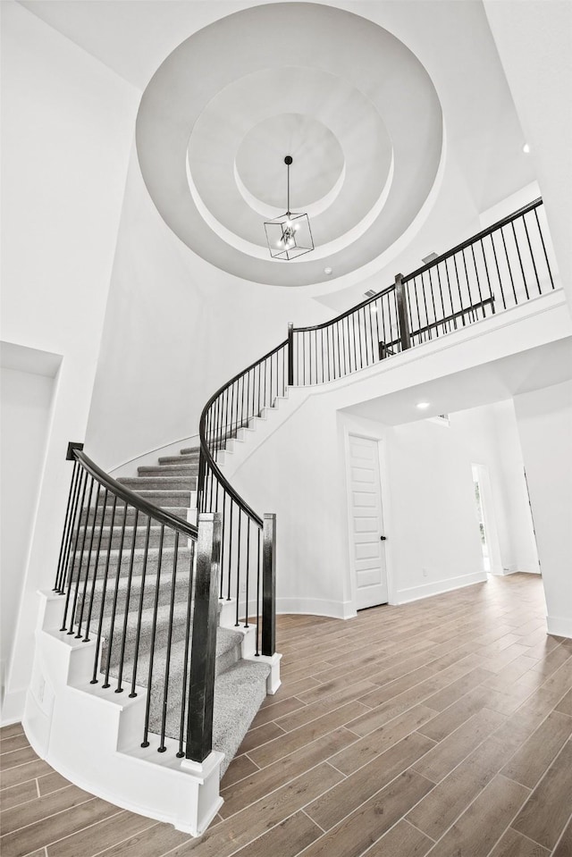 stairs featuring a chandelier, hardwood / wood-style floors, and a towering ceiling